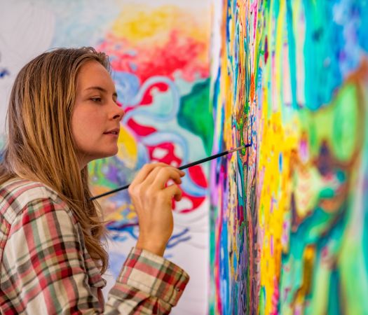 Joyful young female artist painting on the wall