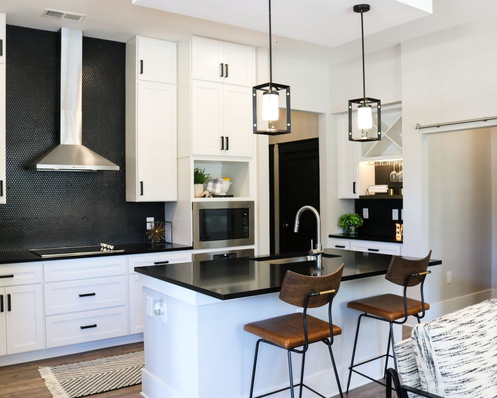 The Village at Commonwealth modern kitchen with high ceilings, custom cabinetry, penny tile backsplash, and stainless steel appliances