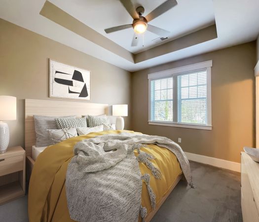 The Village at Commonwealth apartment bedroom with tray ceiling and fan, carpeting, and modern furnishings