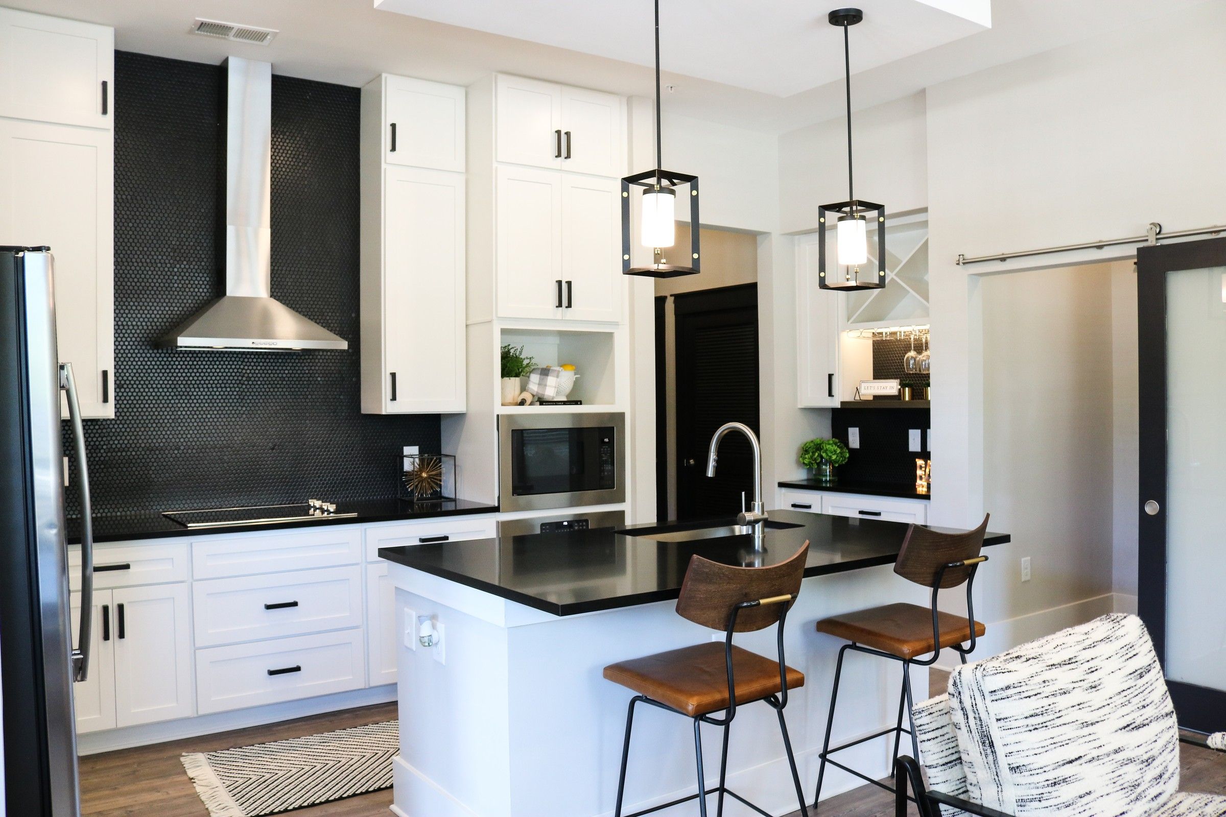 The Village at Commonwealth modern kitchen with high ceilings, custom cabinetry, penny tile backsplash, and stainless steel appliances