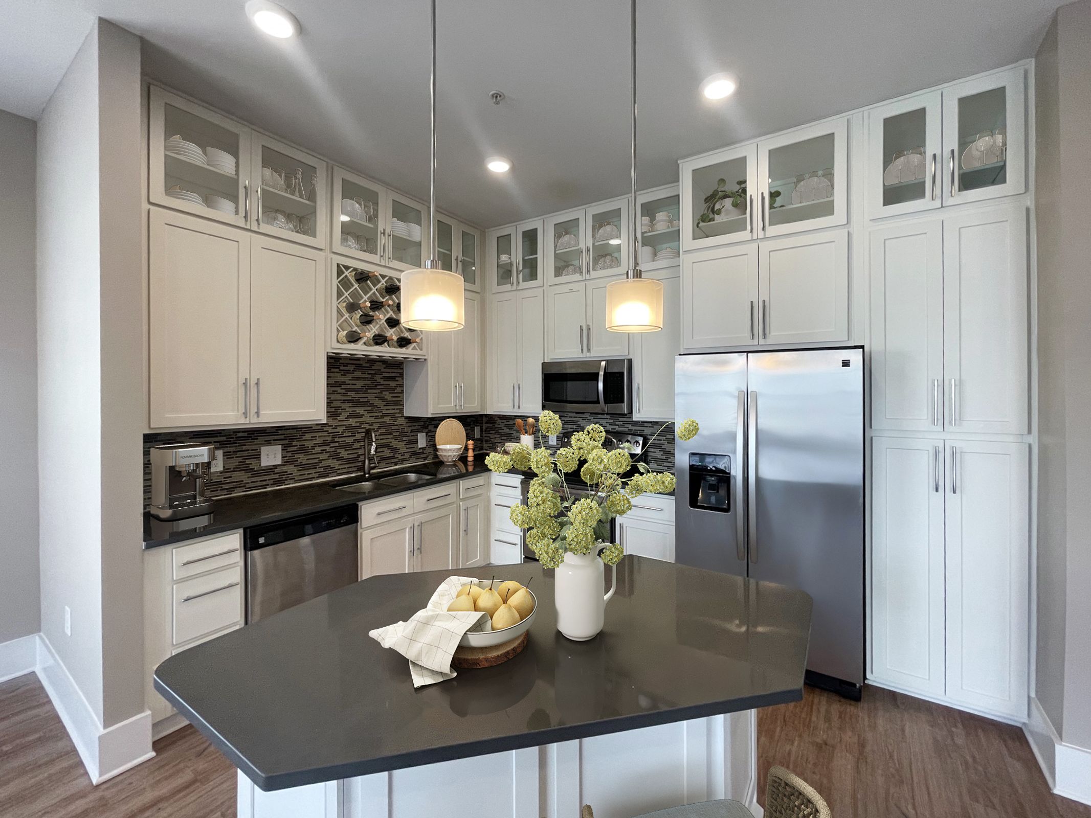 The Village at Commonwealth apartment monochromatic kitchen with decorative tile work, island, and stainless steel appliances