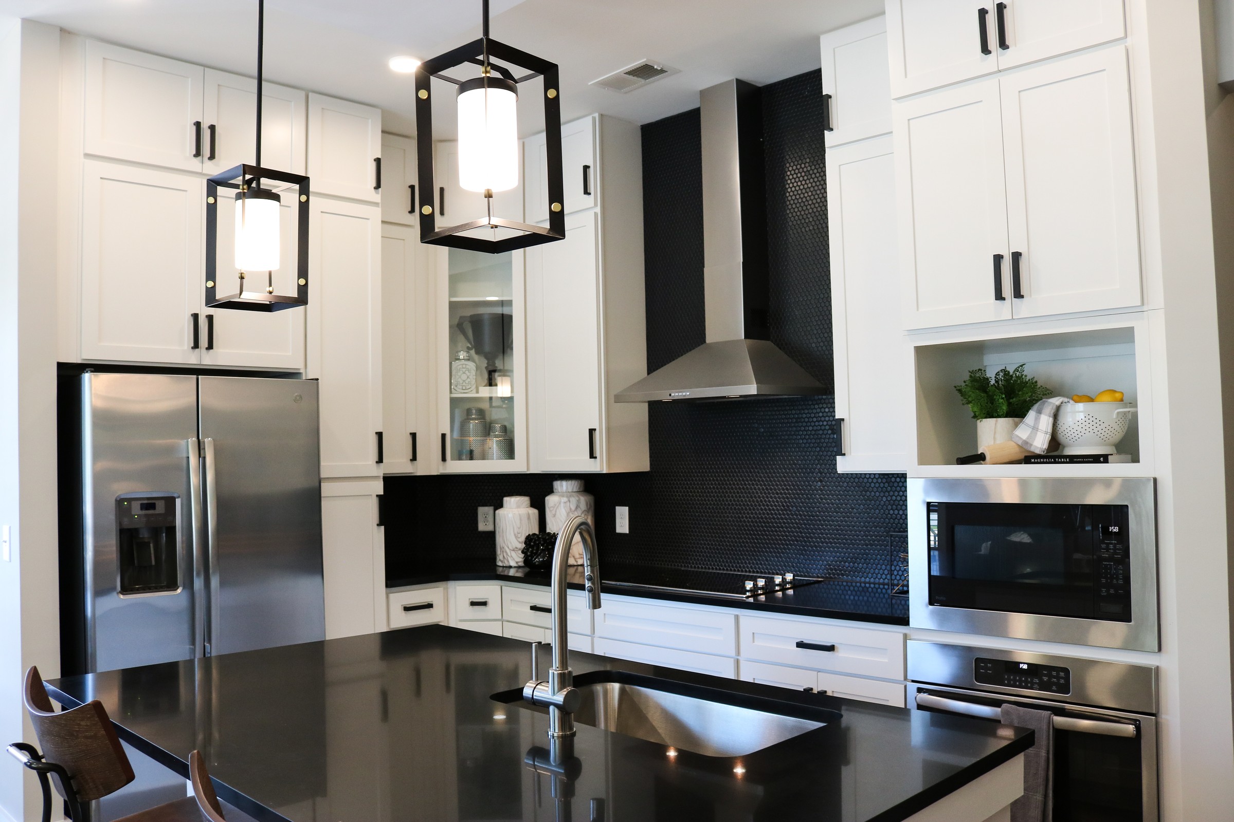 The Village at Commonwealth modern kitchen with high ceilings, custom cabinetry, penny tile backsplash, and stainless steel appliances